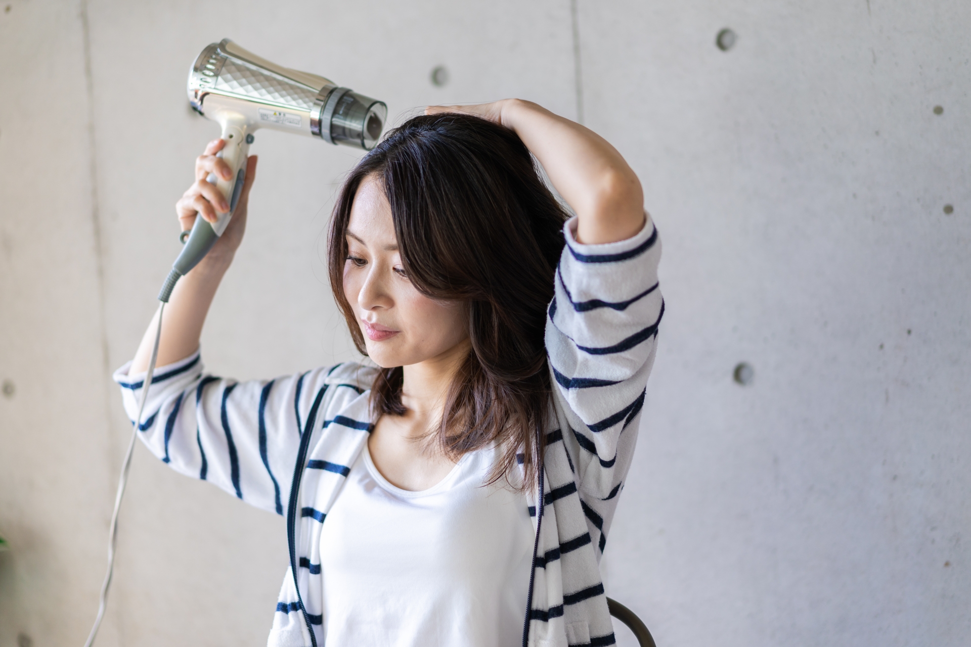 ドライヤーで髪の毛を乾かす女性