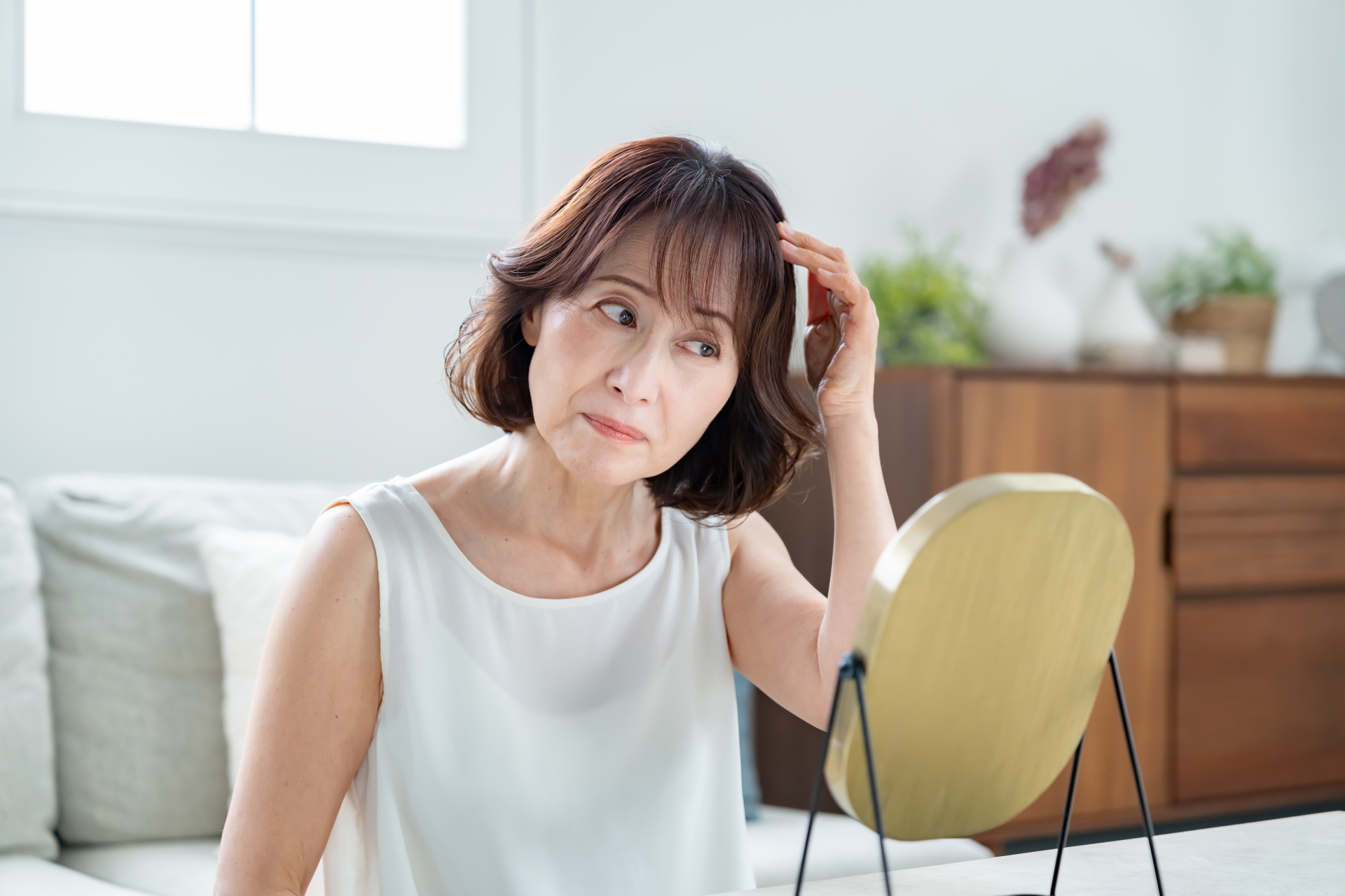 鏡を見て白髪を気にしている女性